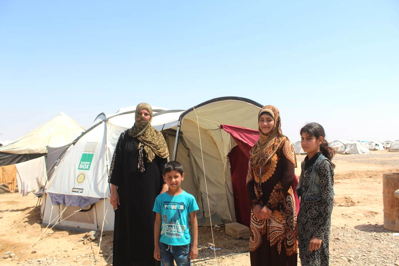 Asmahan and her family standing outside their new home.