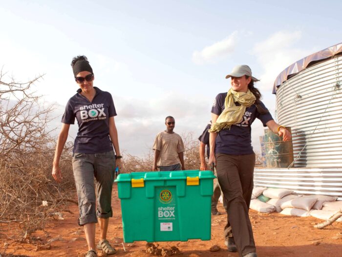 ShelterBox Response Team members carrying a ShelterBox at Haloweyn Refugee Camp in Ethiopia