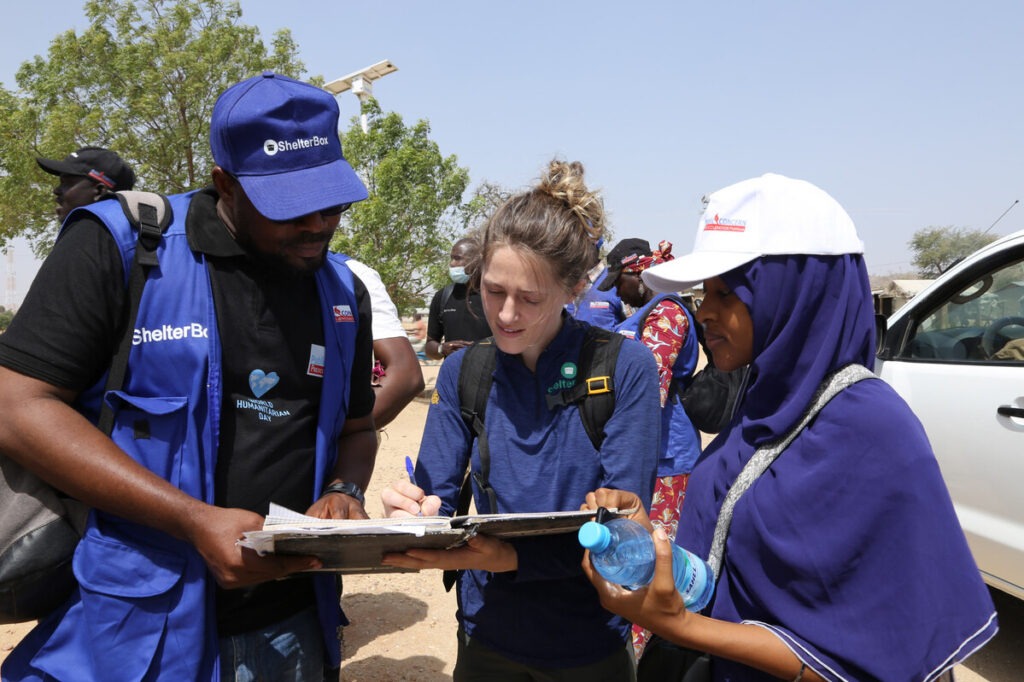Three people looking at a clipboard in Minawao camp in Cameroon.