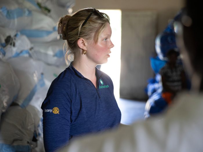 Woman wearing blue next to bundles of aid in Malawi