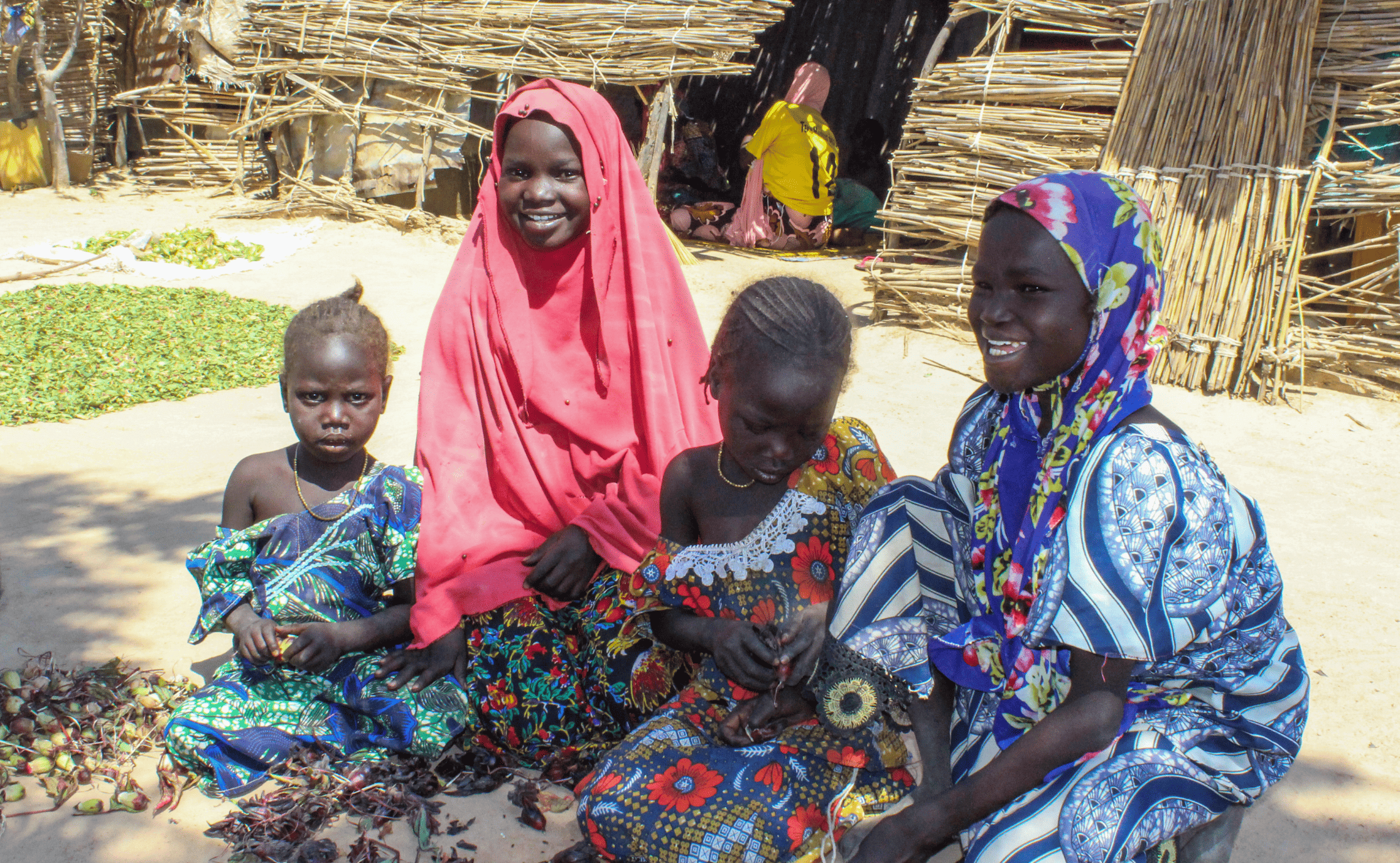 Four children sit outside temporary shelters in a displacement camp in northern Cameroon.